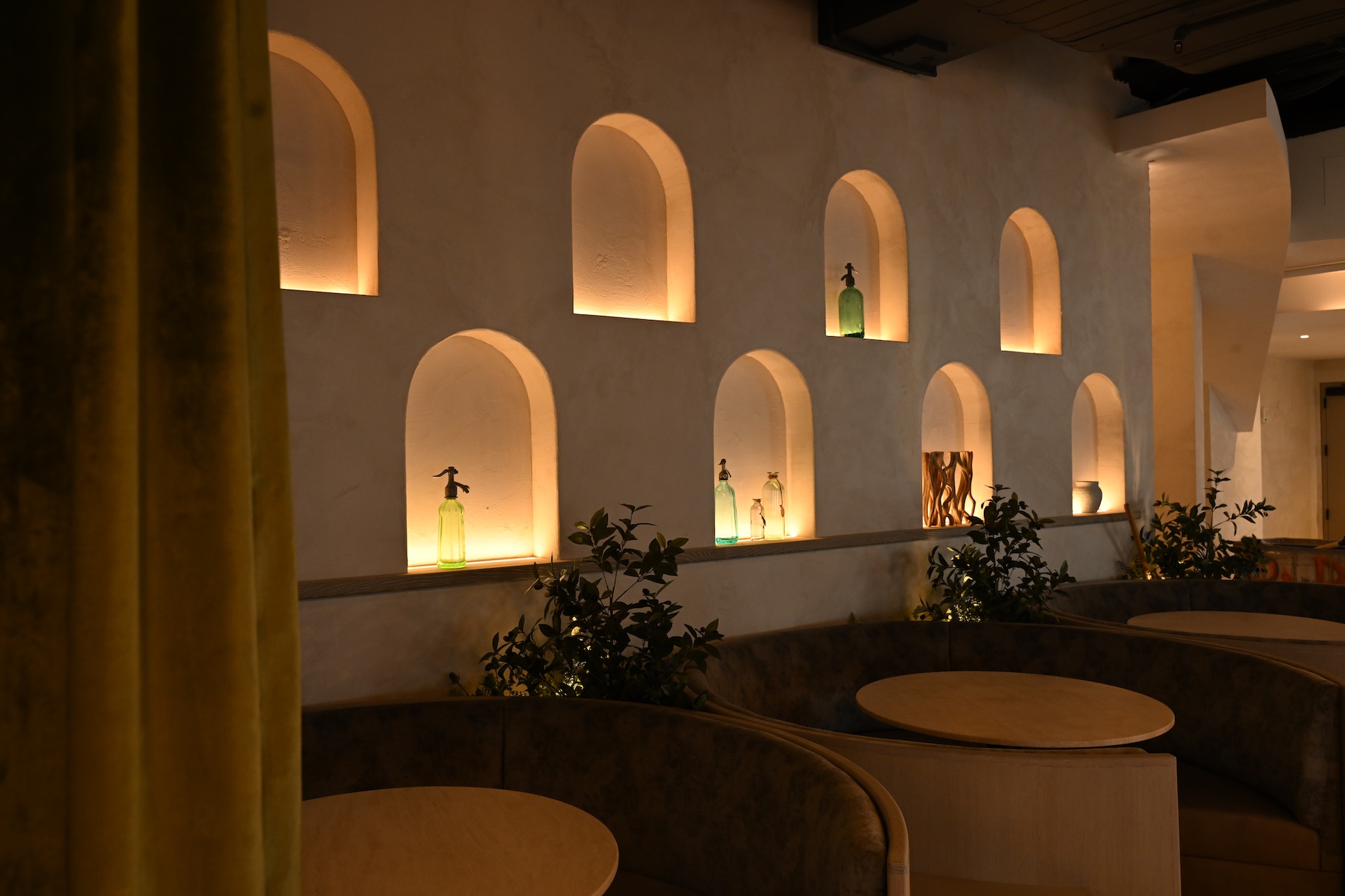 Hand-applied plaster wall with illuminated arched niches in a warm interior